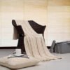 Cable Κουβέρτα Καναπέ Natural πλεκτή απλωμένη σε καρέκλα με μαξιλάρι δαπέδου