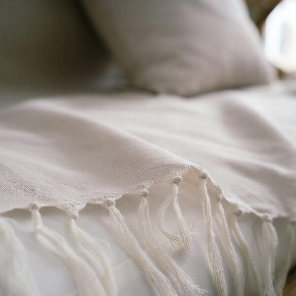 Eartha Ριχτάρι Sail Cloth Beige 372/06 3 Διαστάσεις με κρόσια στρωμένο σε καναπέ με μαξιλάρι